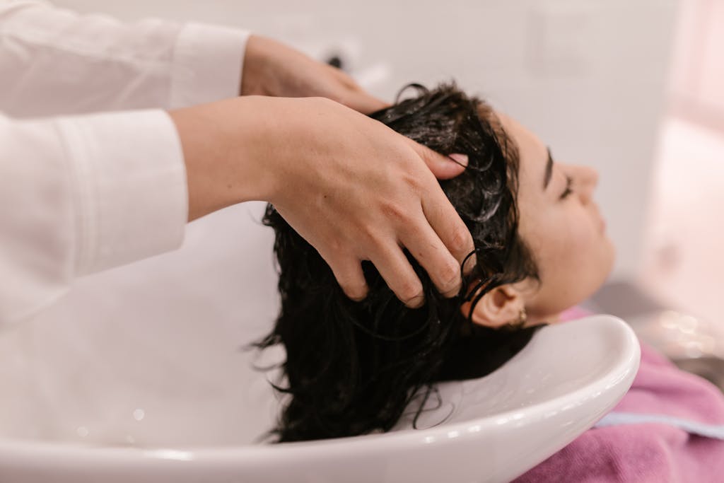 A woman enjoys a relaxing hair wash at a salon. Captured in a cozy indoor setting.