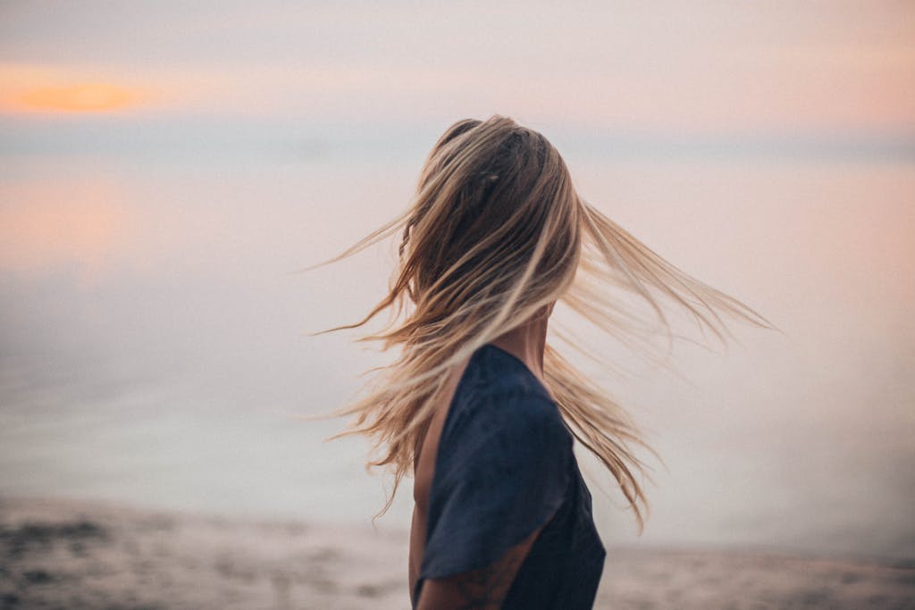 Blonde woman enjoying a serene sunset by the beach, capturing the essence of tranquility.